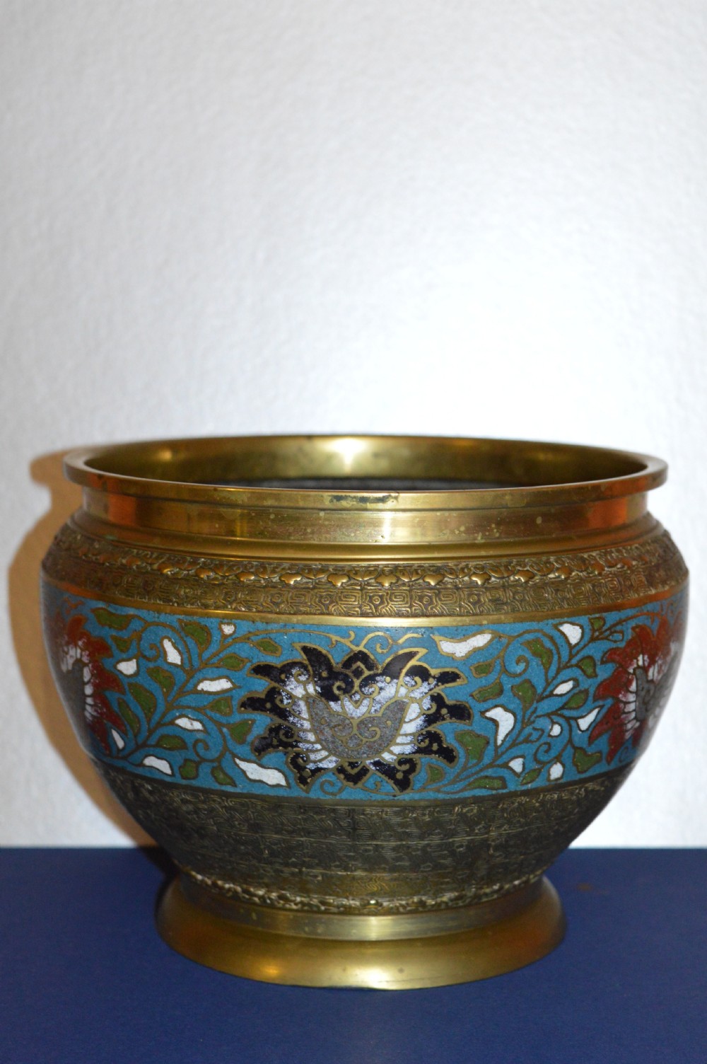 A rounded antique Chinese bronze and cloisonne enamel bowl featuring turquoise ground with floral scroll patterns and a brass rim and base.