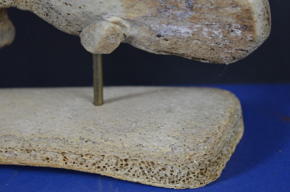 A hand-carved whale figure made from porous whalebone mounted on a metal pin above a rectangular bone plinth base. View IV