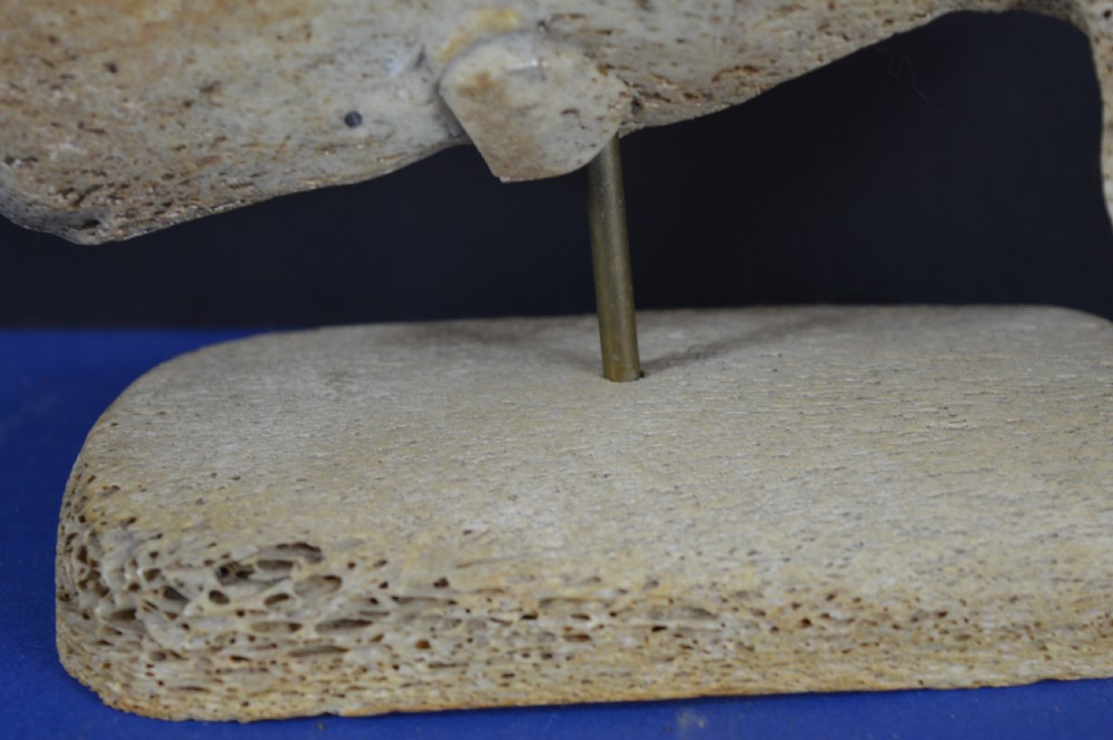 A hand-carved whale figure made from porous whalebone mounted on a metal pin above a rectangular bone plinth base. View IX