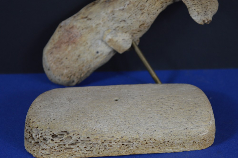 A hand-carved whale figure made from porous whalebone mounted on a metal pin above a rectangular bone plinth base. View XI
