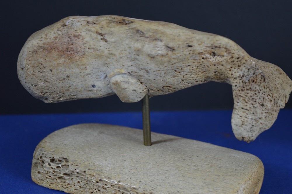 A hand-carved whale figure made from porous whalebone mounted on a metal pin above a rectangular bone plinth base. View XIII