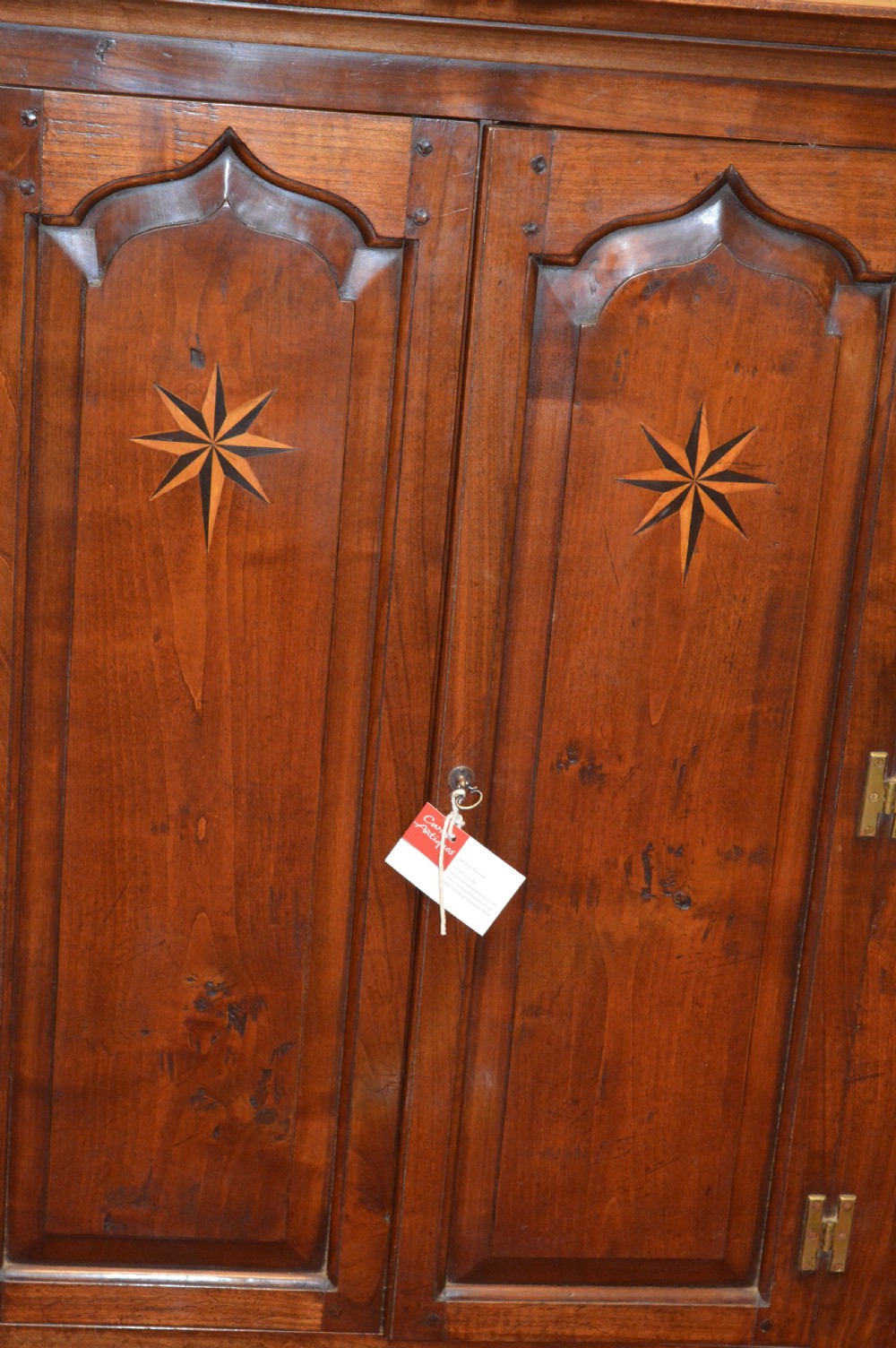 A nineteenth-century mahogany corner hanging cupboard featuring twin panelled doors with inlaid star motifs and brass H-hinges. View II