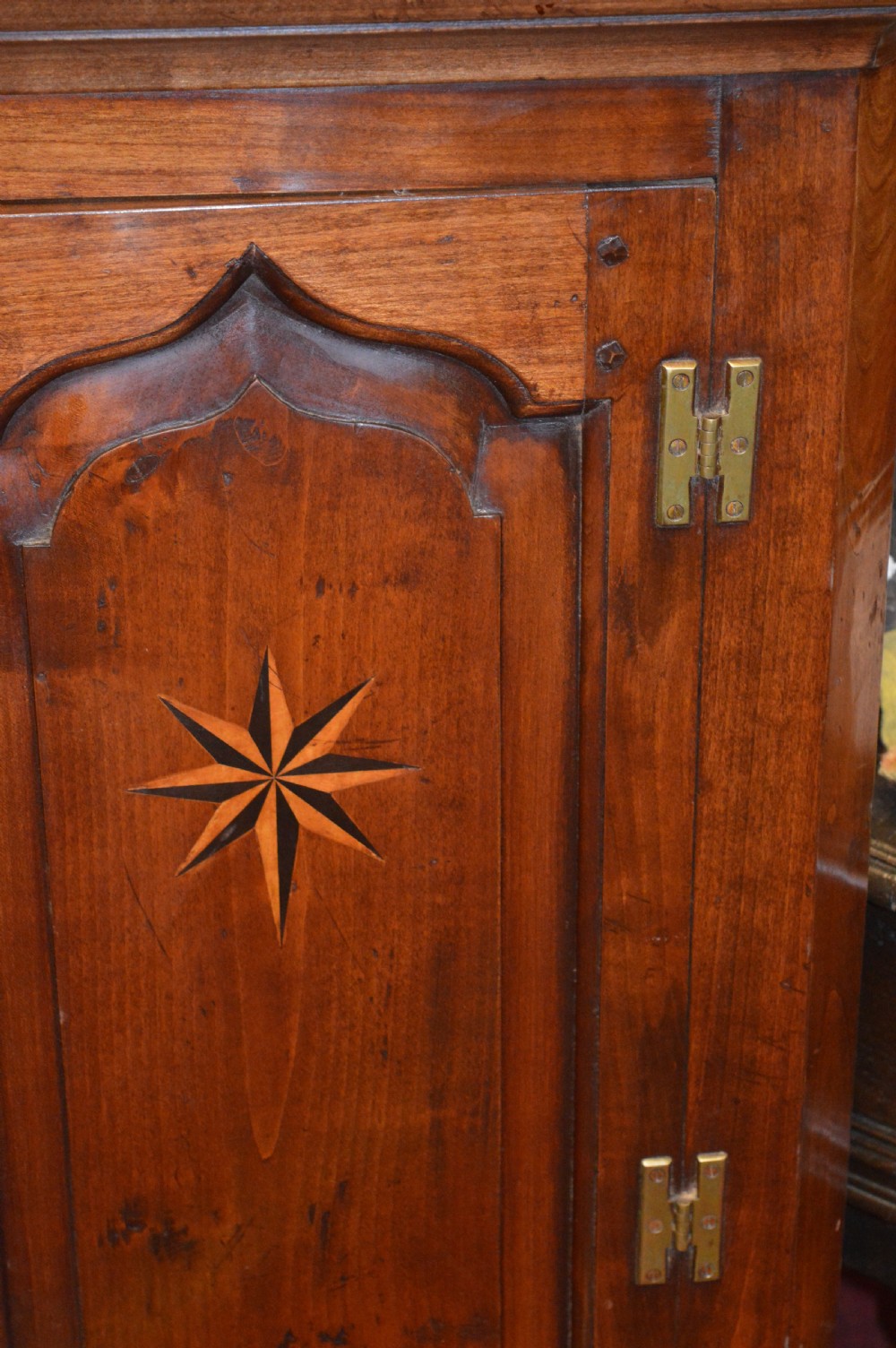 A nineteenth-century mahogany corner hanging cupboard featuring twin panelled doors with inlaid star motifs and brass H-hinges. View IV