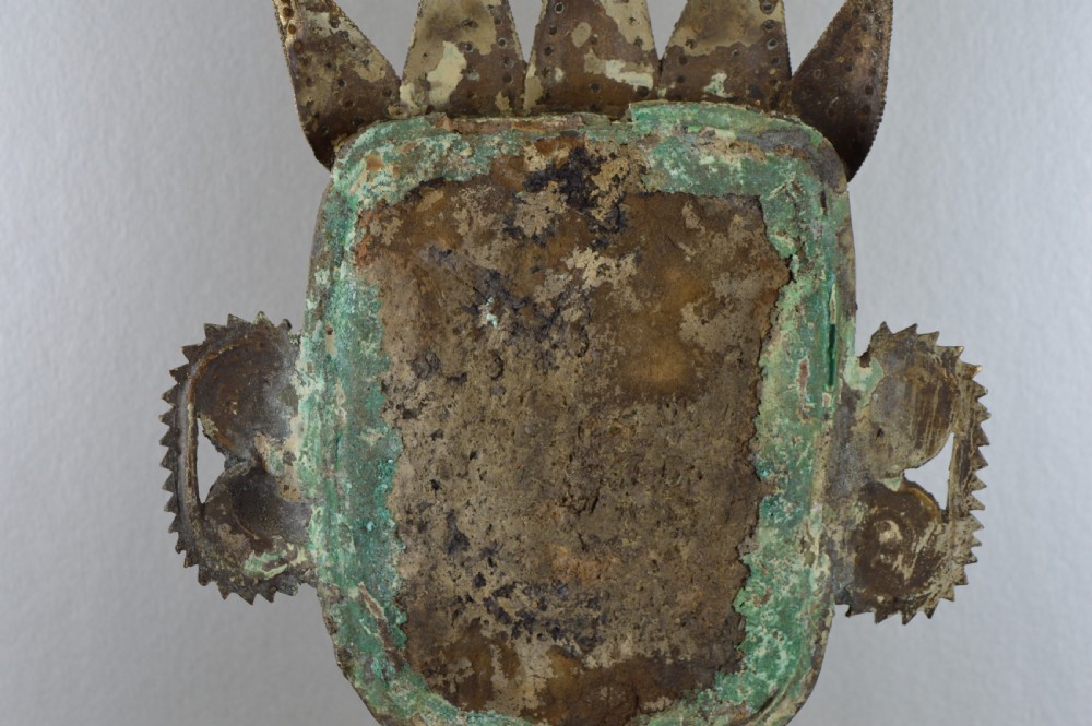 A tall, cast brass African statue featuring a stylized king figure with a spiked crown, elaborate facial details, and a tapered cylindrical base. View X