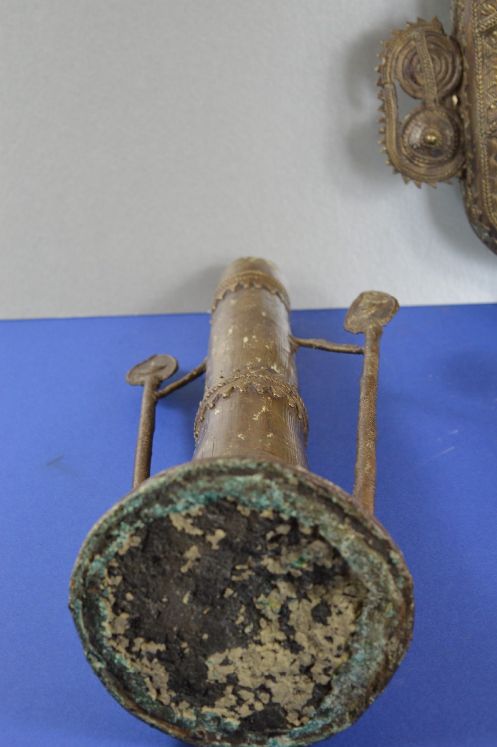 A tall, cast brass African statue featuring a stylized king figure with a spiked crown, elaborate facial details, and a tapered cylindrical base. View XII