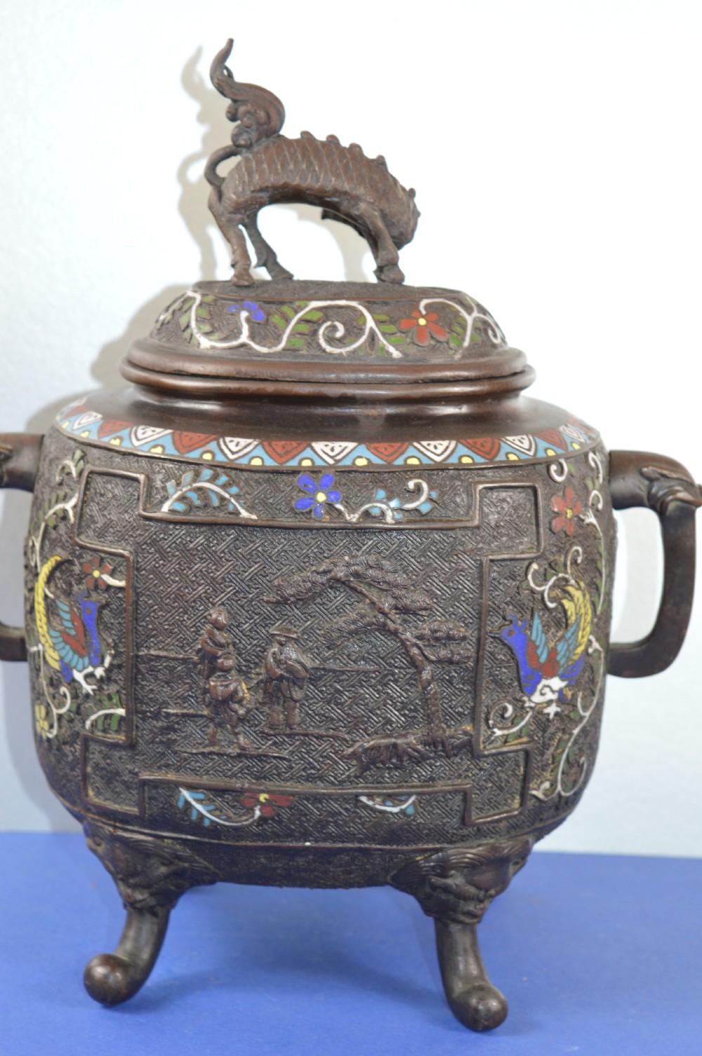 A late nineteenth-century Japanese bronze tripod censer featuring polychrome cloisonne enamel work, relief panels depicting a sailboat, loop handles, and a cover topped with a beast finial. View VI