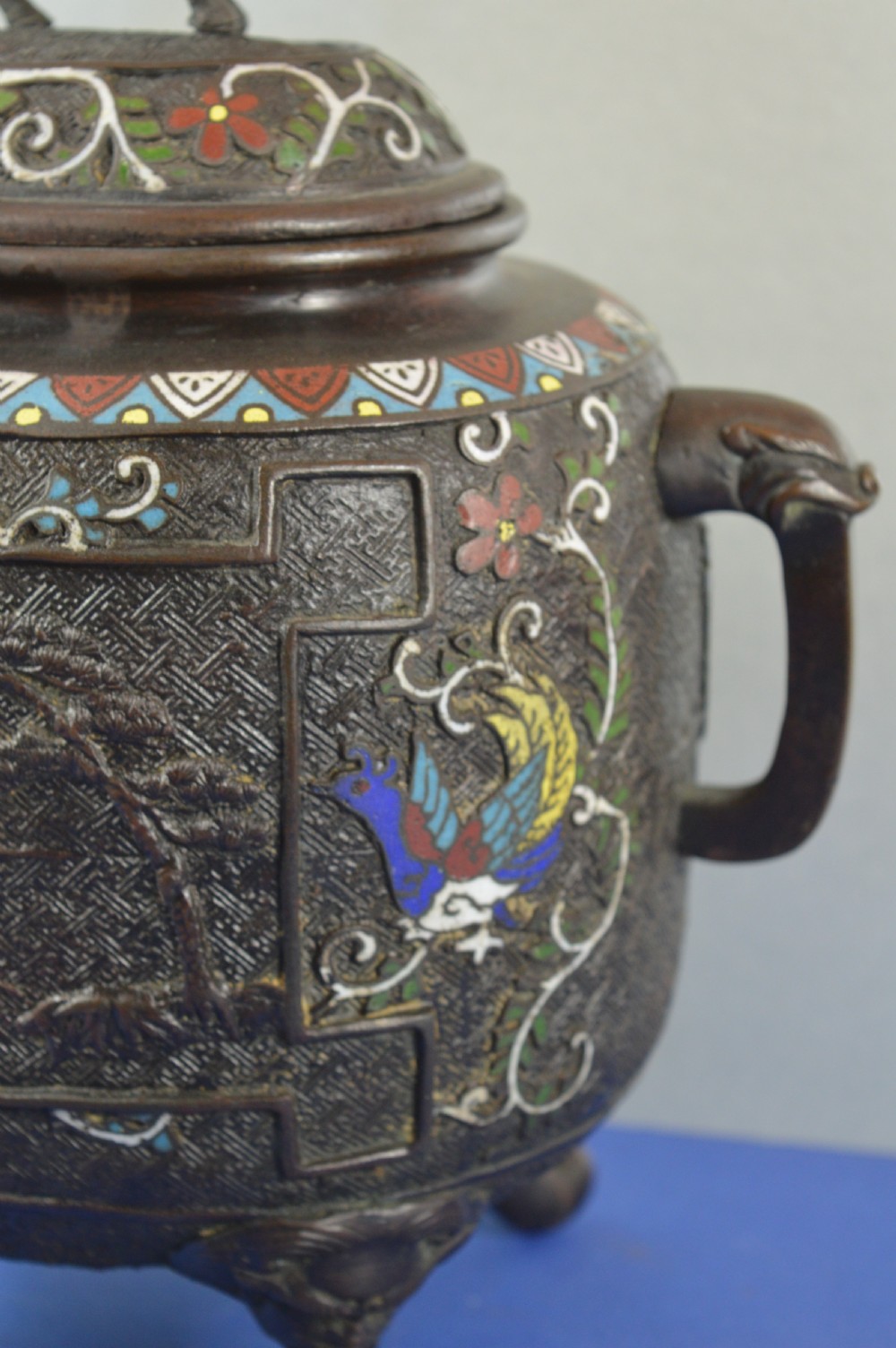 A late nineteenth-century Japanese bronze tripod censer featuring polychrome cloisonne enamel work, relief panels depicting a sailboat, loop handles, and a cover topped with a beast finial. View VII