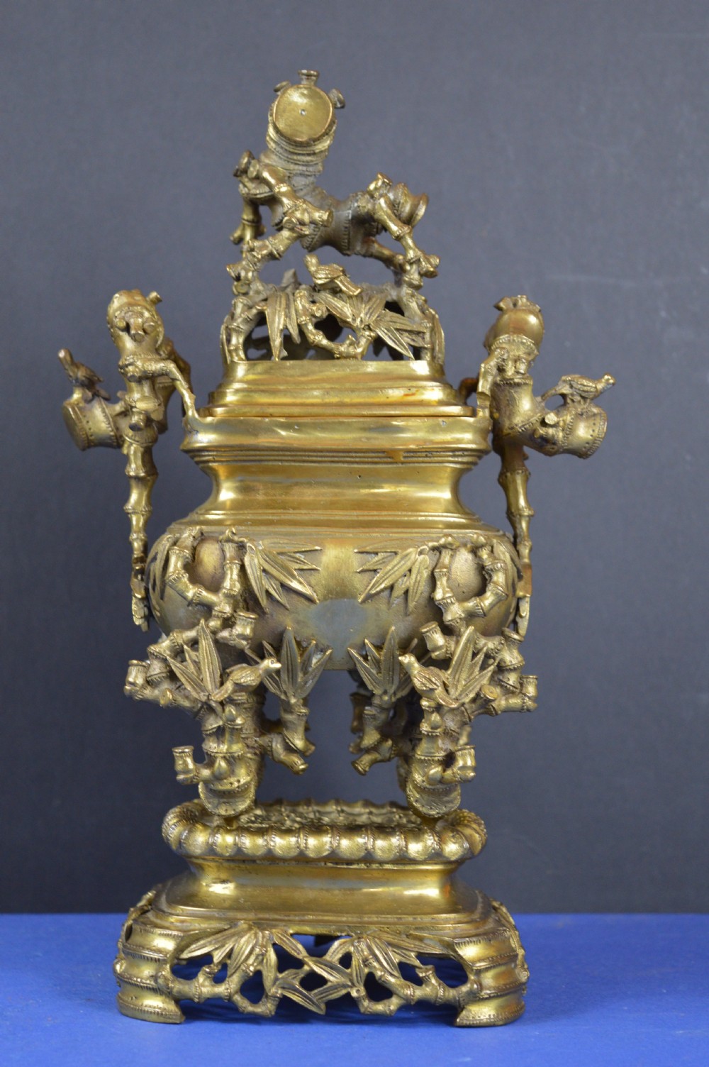 An ornate 19th-century Chinese cast bronze censer featuring bamboo leaf reliefs, sculpted handles, a pierced lid, and an intricate tiered base.