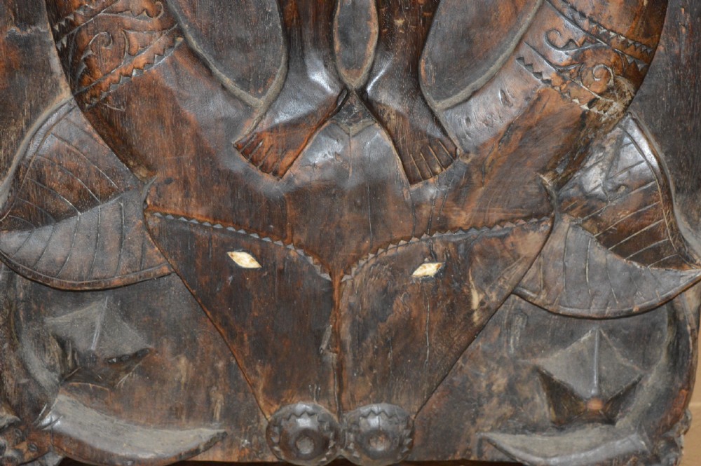 Pair of dark hand-carved wooden doors featuring high-relief human figures holding roosters above water buffalo heads with bone inlaid eyes. View XIV