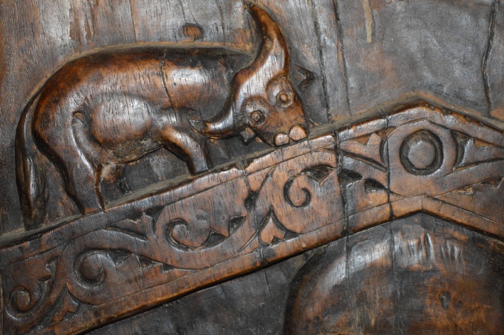 Pair of dark hand-carved wooden doors featuring high-relief human figures holding roosters above water buffalo heads with bone inlaid eyes. View XVII