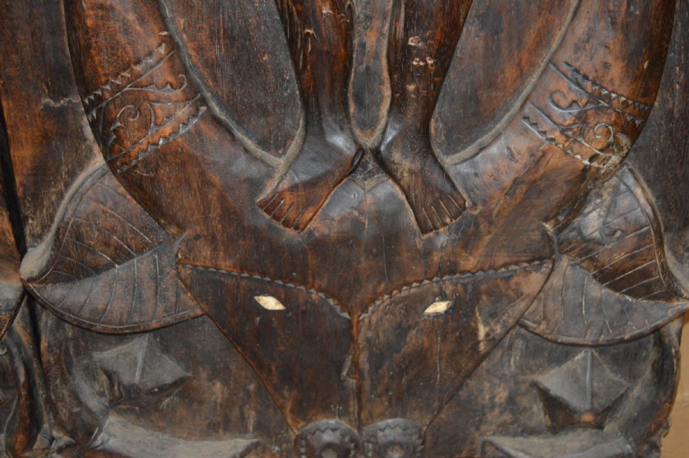 Pair of dark hand-carved wooden doors featuring high-relief human figures holding roosters above water buffalo heads with bone inlaid eyes. View XX