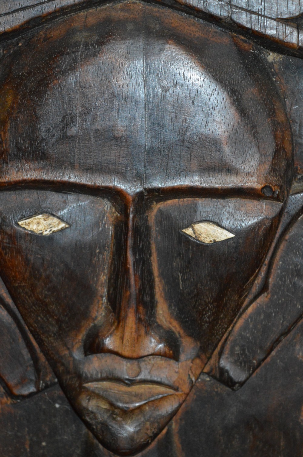 Pair of dark hand-carved wooden doors featuring high-relief human figures holding roosters above water buffalo heads with bone inlaid eyes. View XXI