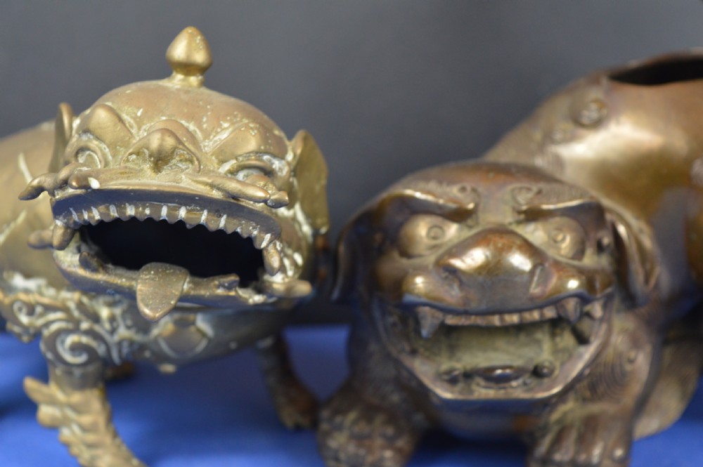 A pair of antique cast bronze Chinese foo dog incense burners with carved scroll details and open mouths. View II