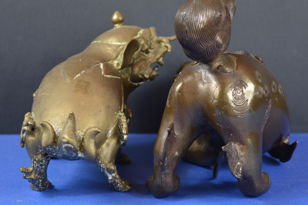 A pair of antique cast bronze Chinese foo dog incense burners with carved scroll details and open mouths. View IV