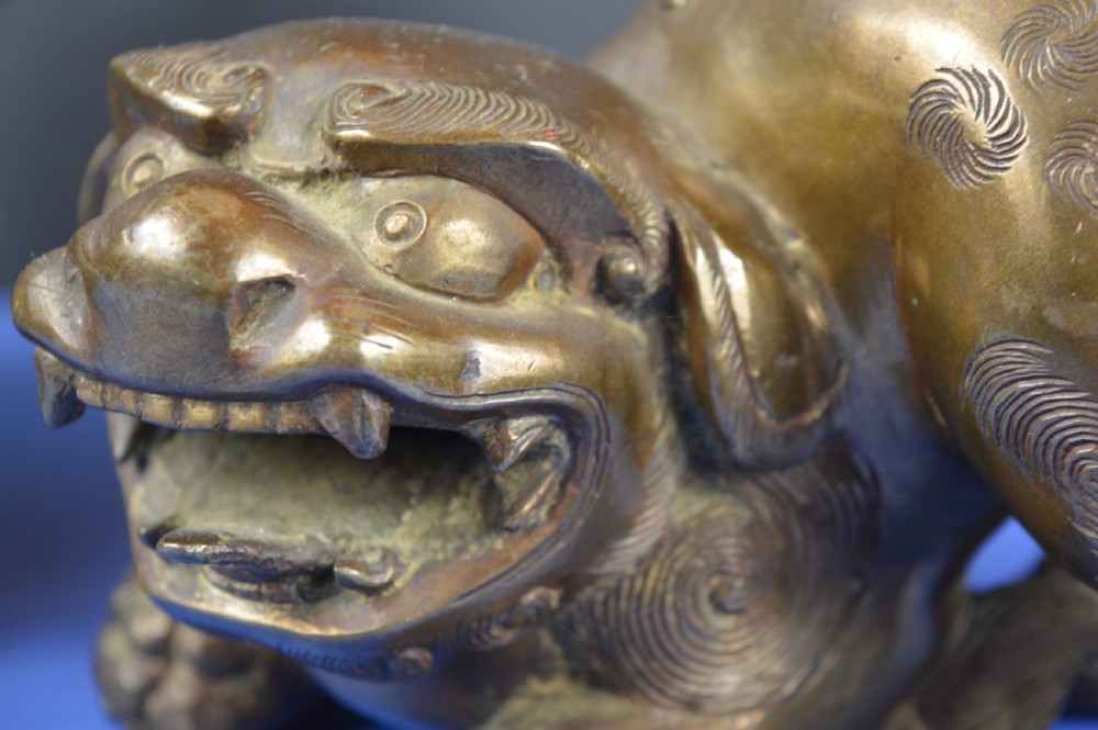 A pair of antique cast bronze Chinese foo dog incense burners with carved scroll details and open mouths. View V