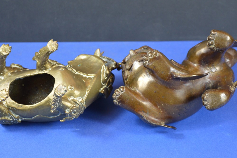 A pair of antique cast bronze Chinese foo dog incense burners with carved scroll details and open mouths. View IX