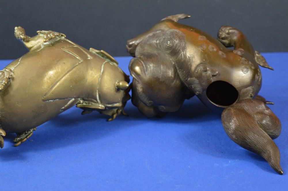 A pair of antique cast bronze Chinese foo dog incense burners with carved scroll details and open mouths. View X