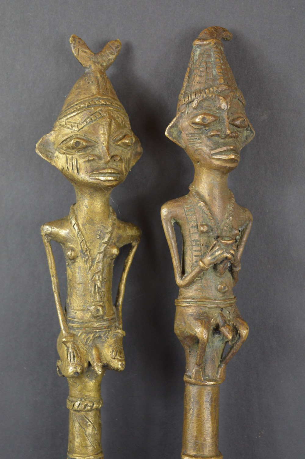 A pair of cast bronze Yoruba ceremonial staffs featuring sculpted human figures as finials above flat, patterned brass blades. View II