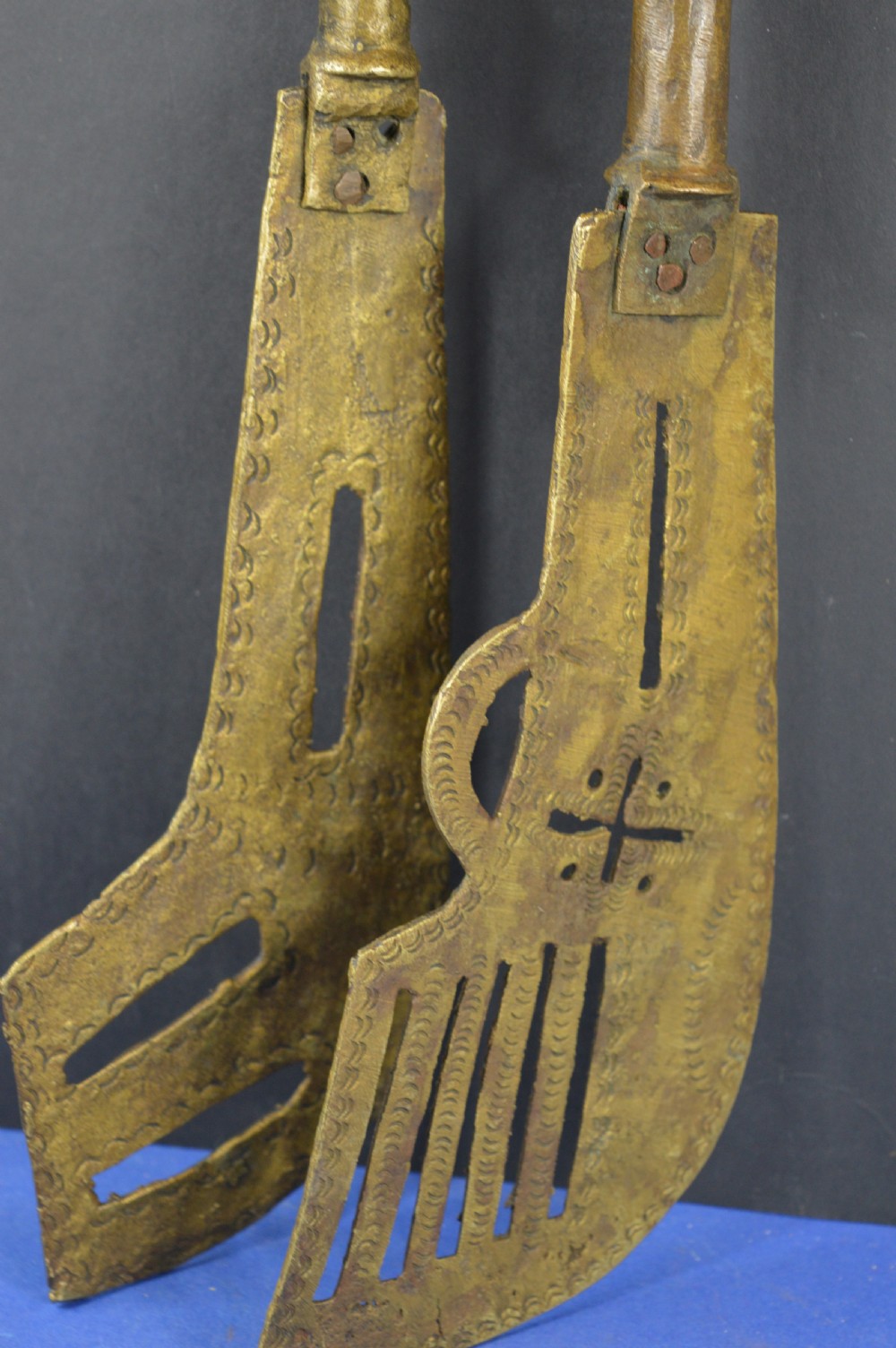 A pair of cast bronze Yoruba ceremonial staffs featuring sculpted human figures as finials above flat, patterned brass blades. View III