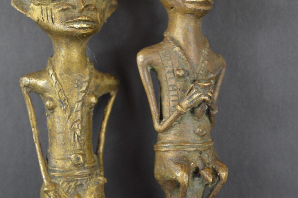A pair of cast bronze Yoruba ceremonial staffs featuring sculpted human figures as finials above flat, patterned brass blades. View V