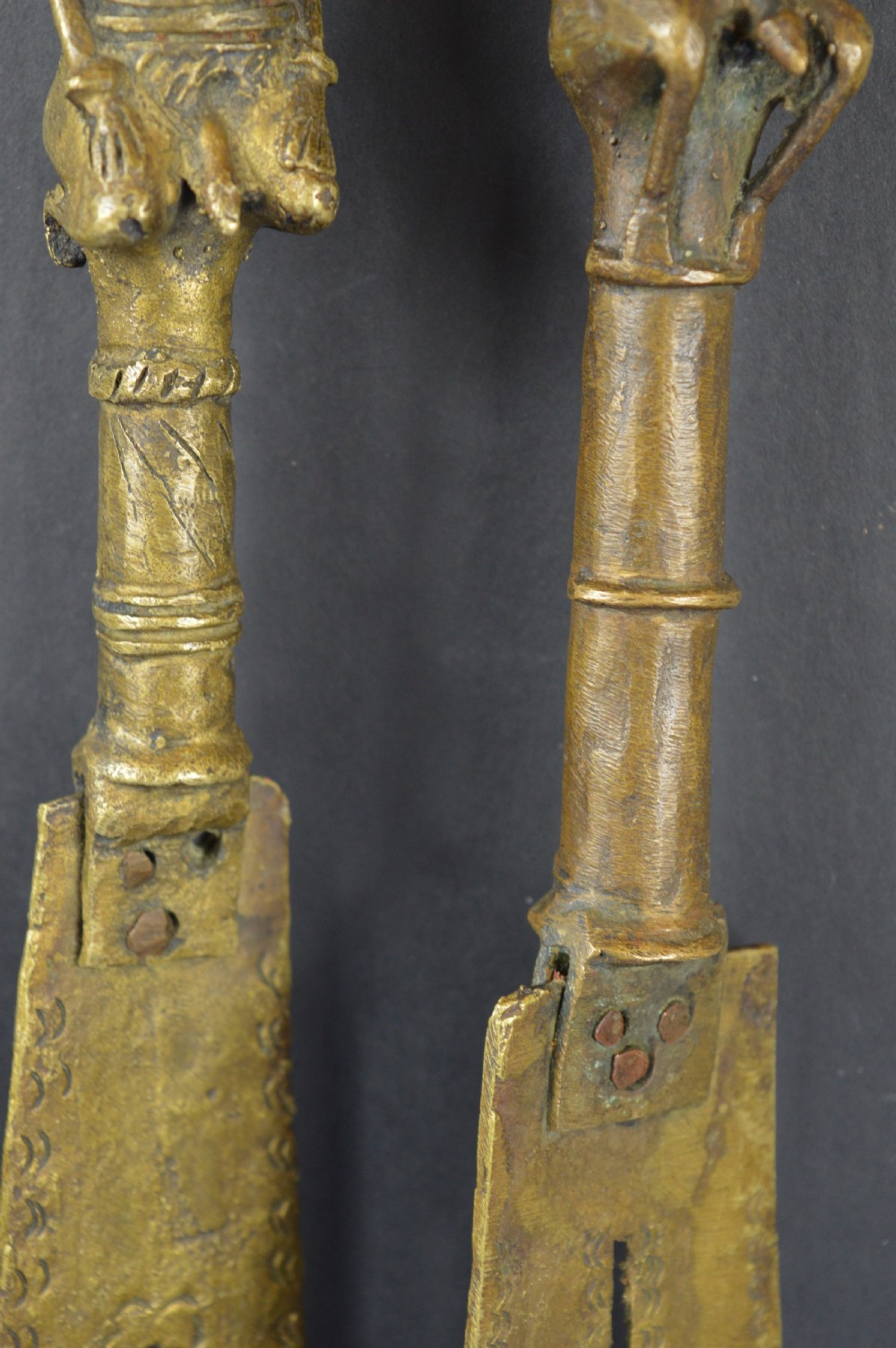 A pair of cast bronze Yoruba ceremonial staffs featuring sculpted human figures as finials above flat, patterned brass blades. View VI