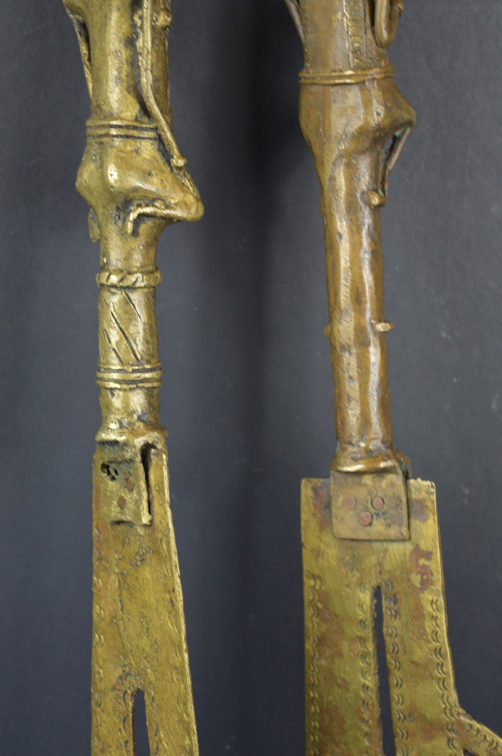 A pair of cast bronze Yoruba ceremonial staffs featuring sculpted human figures as finials above flat, patterned brass blades. View X