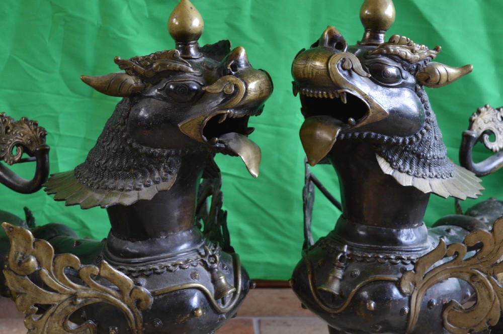 A pair of substantial dark bronze Tibetan temple lions featuring raised tails, stylised scale details, and brass accents. View II