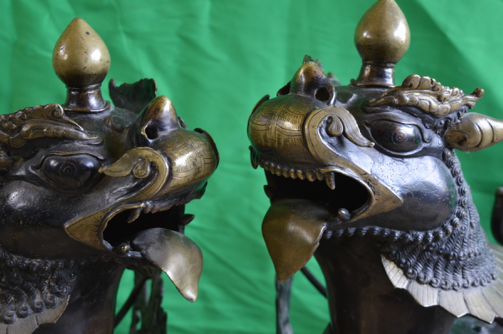 A pair of substantial dark bronze Tibetan temple lions featuring raised tails, stylised scale details, and brass accents. View IV