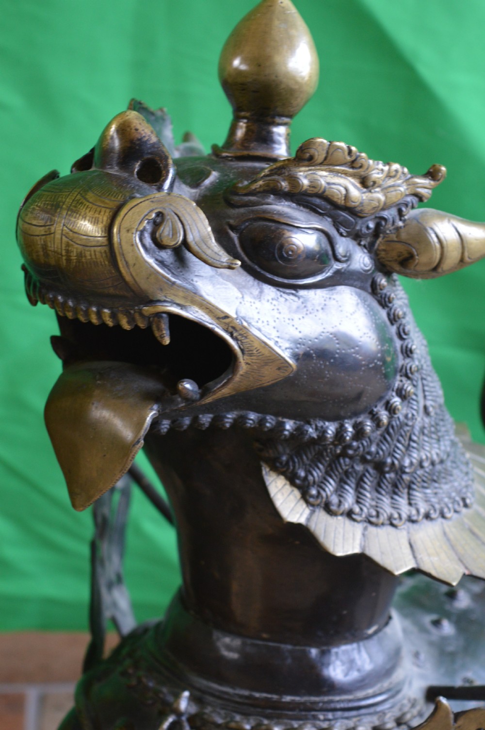 A pair of substantial dark bronze Tibetan temple lions featuring raised tails, stylised scale details, and brass accents. View VI