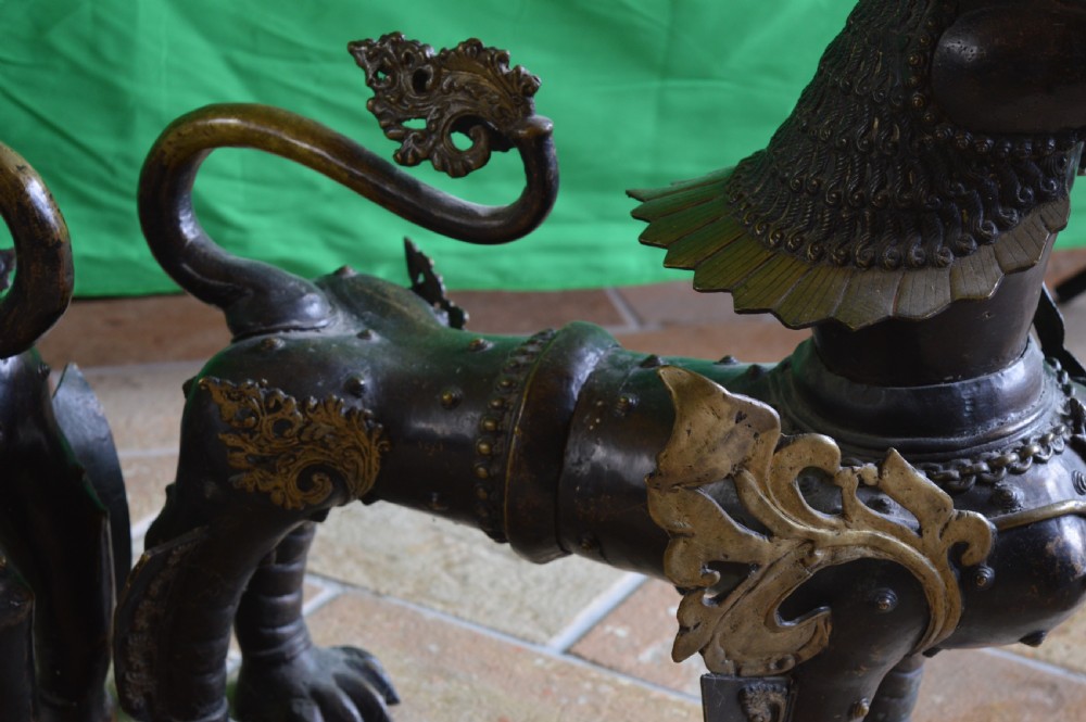 A pair of substantial dark bronze Tibetan temple lions featuring raised tails, stylised scale details, and brass accents. View VIII