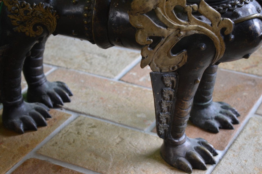 A pair of substantial dark bronze Tibetan temple lions featuring raised tails, stylised scale details, and brass accents. View XI