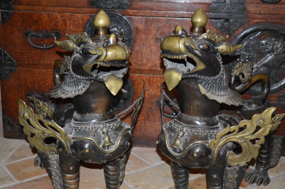 A pair of substantial dark bronze Tibetan temple lions featuring raised tails, stylised scale details, and brass accents. View XXI