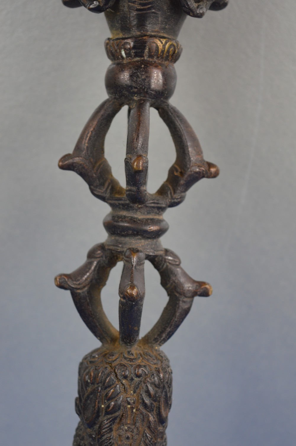 A 19th-century Tibetan bronze phurba featuring a wrathful deity head pommel, central vajra handles, and a three-sided blade extending from a makara mouth. View III