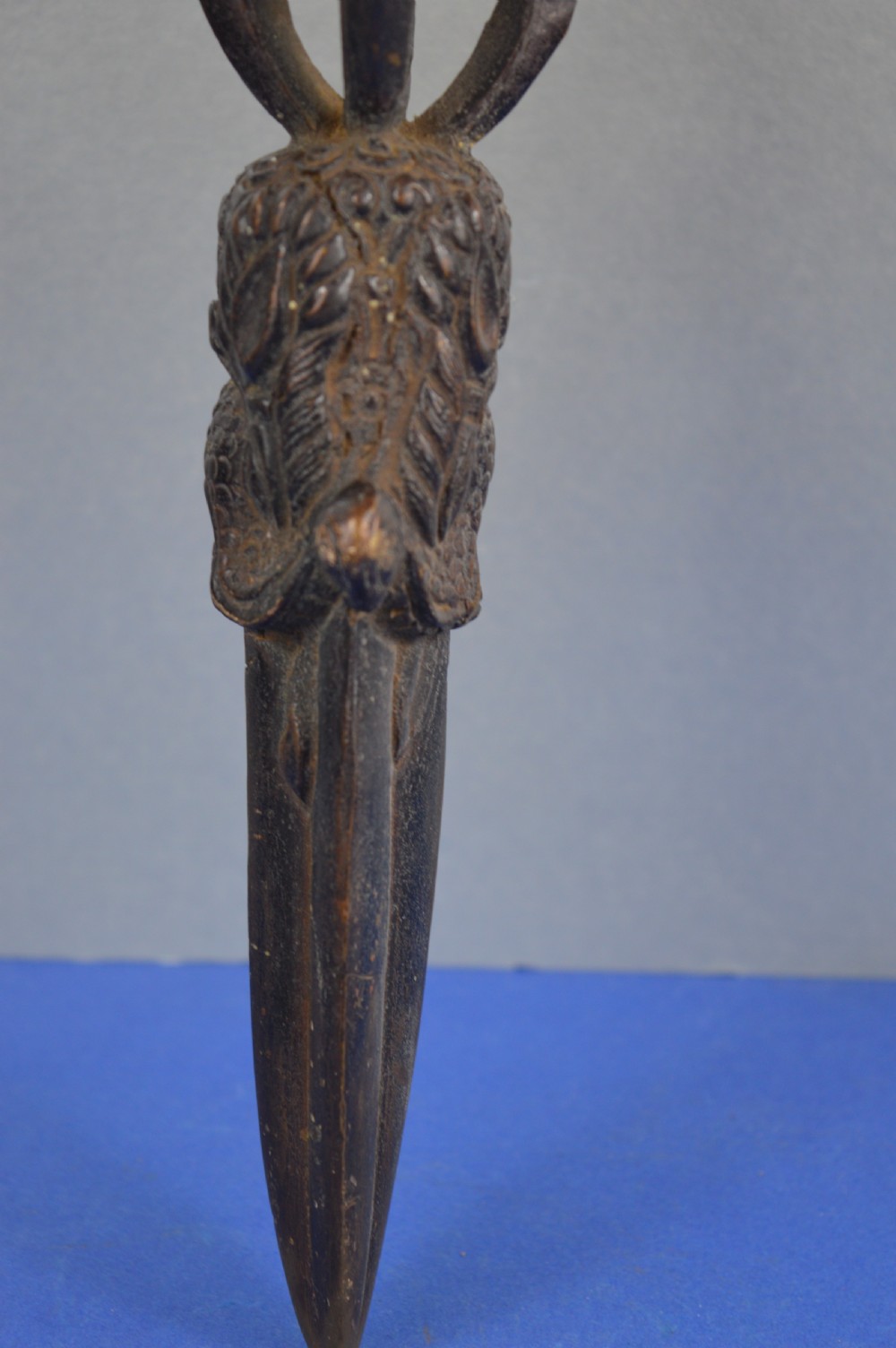 A 19th-century Tibetan bronze phurba featuring a wrathful deity head pommel, central vajra handles, and a three-sided blade extending from a makara mouth. View IV