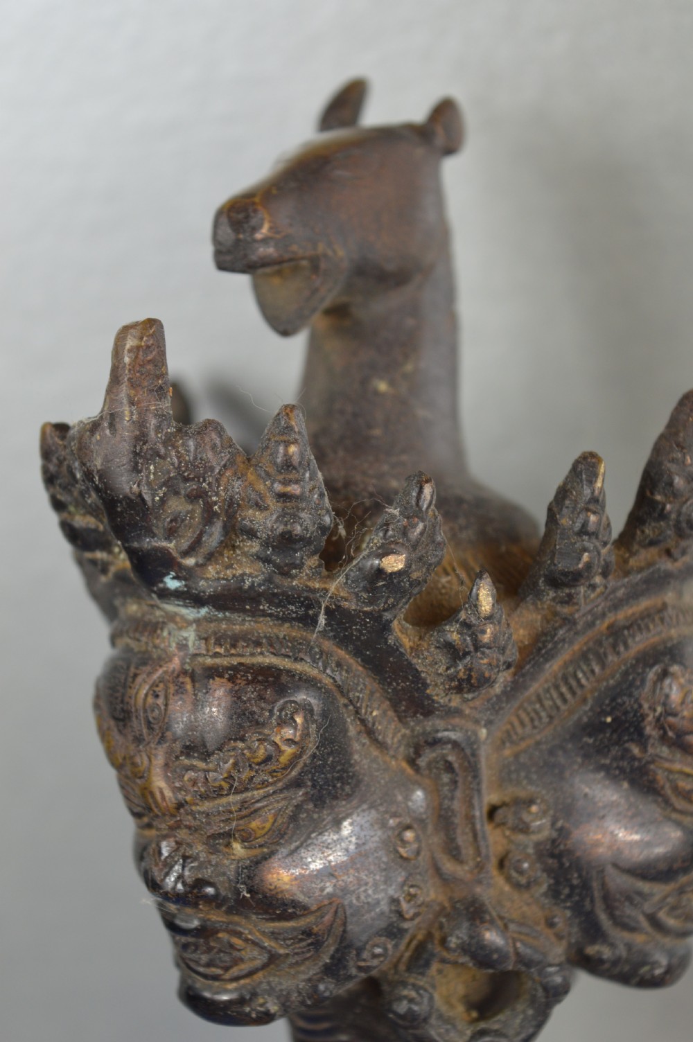 A 19th-century Tibetan bronze phurba featuring a wrathful deity head pommel, central vajra handles, and a three-sided blade extending from a makara mouth. View VII