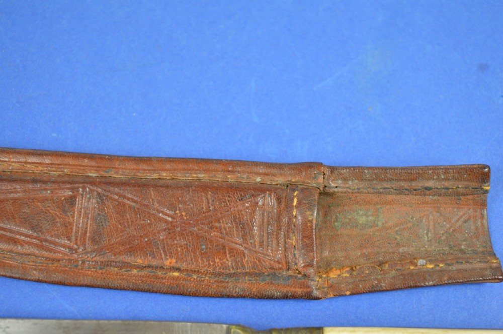 A nineteenth-century Anglo-Afghan war knife featuring a steel blade, a bone handle carved with the word KANDAHAR, and a stamped brown leather sheath. View V