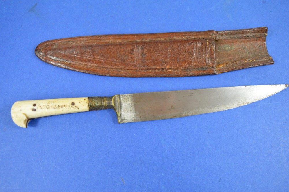 A nineteenth-century Anglo-Afghan war knife featuring a steel blade, a bone handle carved with the word KANDAHAR, and a stamped brown leather sheath. View VII