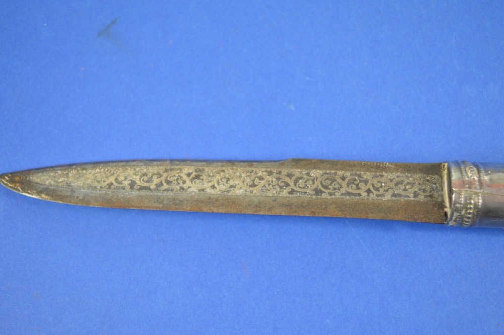 A 19th-century ceremonial knife with a steel blade featuring silver scrollwork inlay, a silver metal collar, and a smooth horn handle. View III