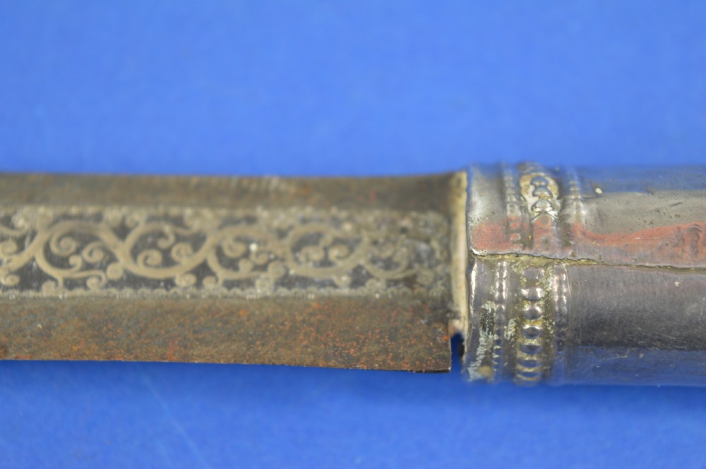 A 19th-century ceremonial knife with a steel blade featuring silver scrollwork inlay, a silver metal collar, and a smooth horn handle. View V