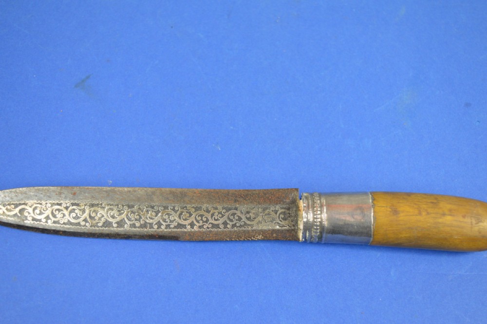 A 19th-century ceremonial knife with a steel blade featuring silver scrollwork inlay, a silver metal collar, and a smooth horn handle. View VII