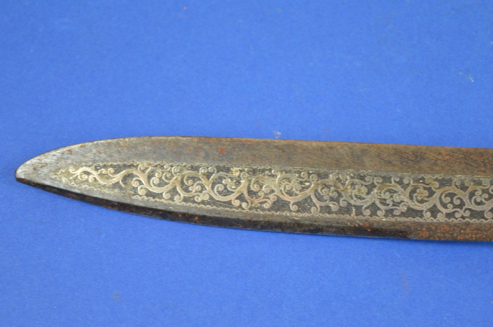 A 19th-century ceremonial knife with a steel blade featuring silver scrollwork inlay, a silver metal collar, and a smooth horn handle. View IX