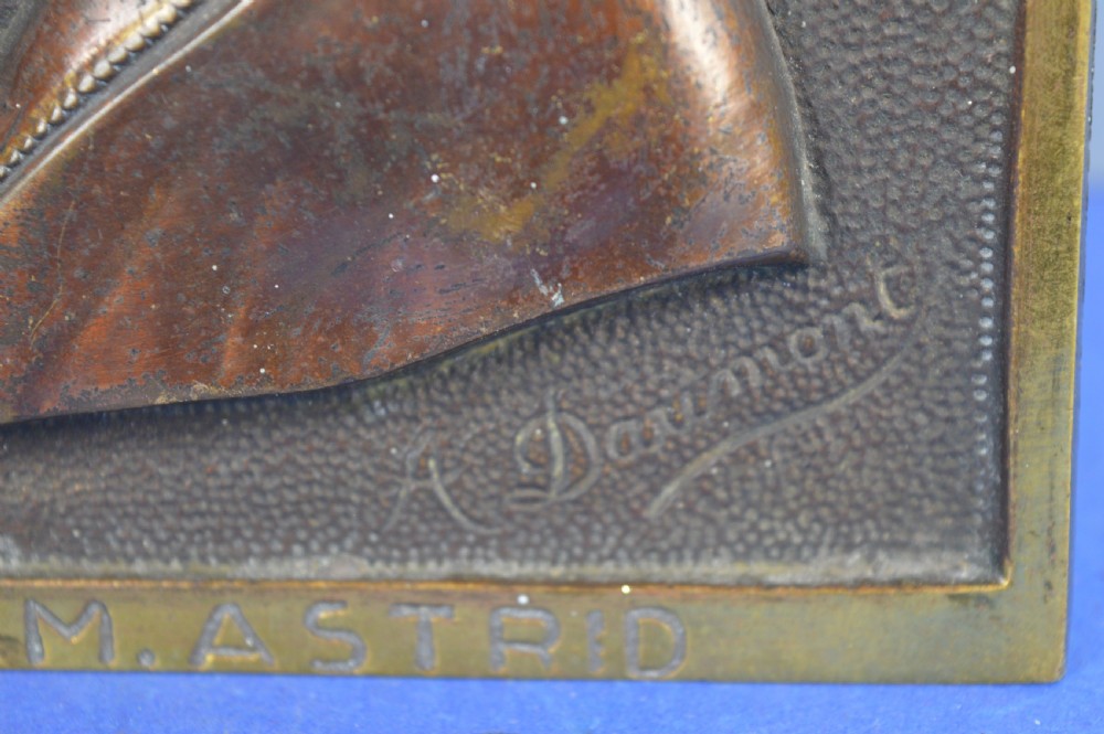 An Art Deco dark brown bronze relief plaque featuring a side profile portrait of Queen Astrid against a textured background with inscribed lettering. View IV