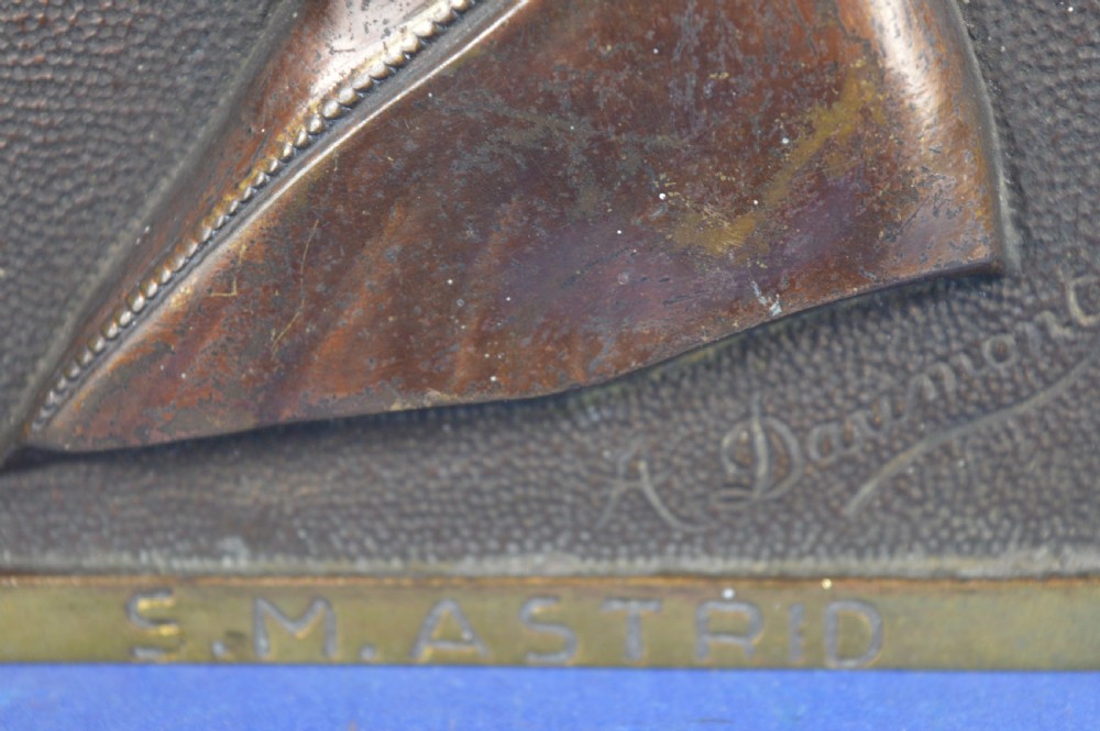 An Art Deco dark brown bronze relief plaque featuring a side profile portrait of Queen Astrid against a textured background with inscribed lettering. View V