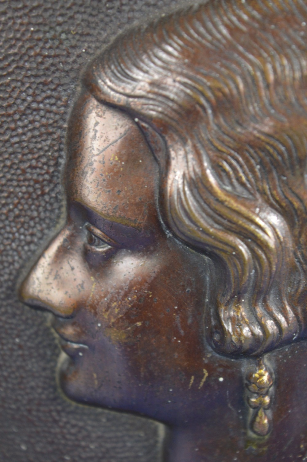 An Art Deco dark brown bronze relief plaque featuring a side profile portrait of Queen Astrid against a textured background with inscribed lettering. View VI