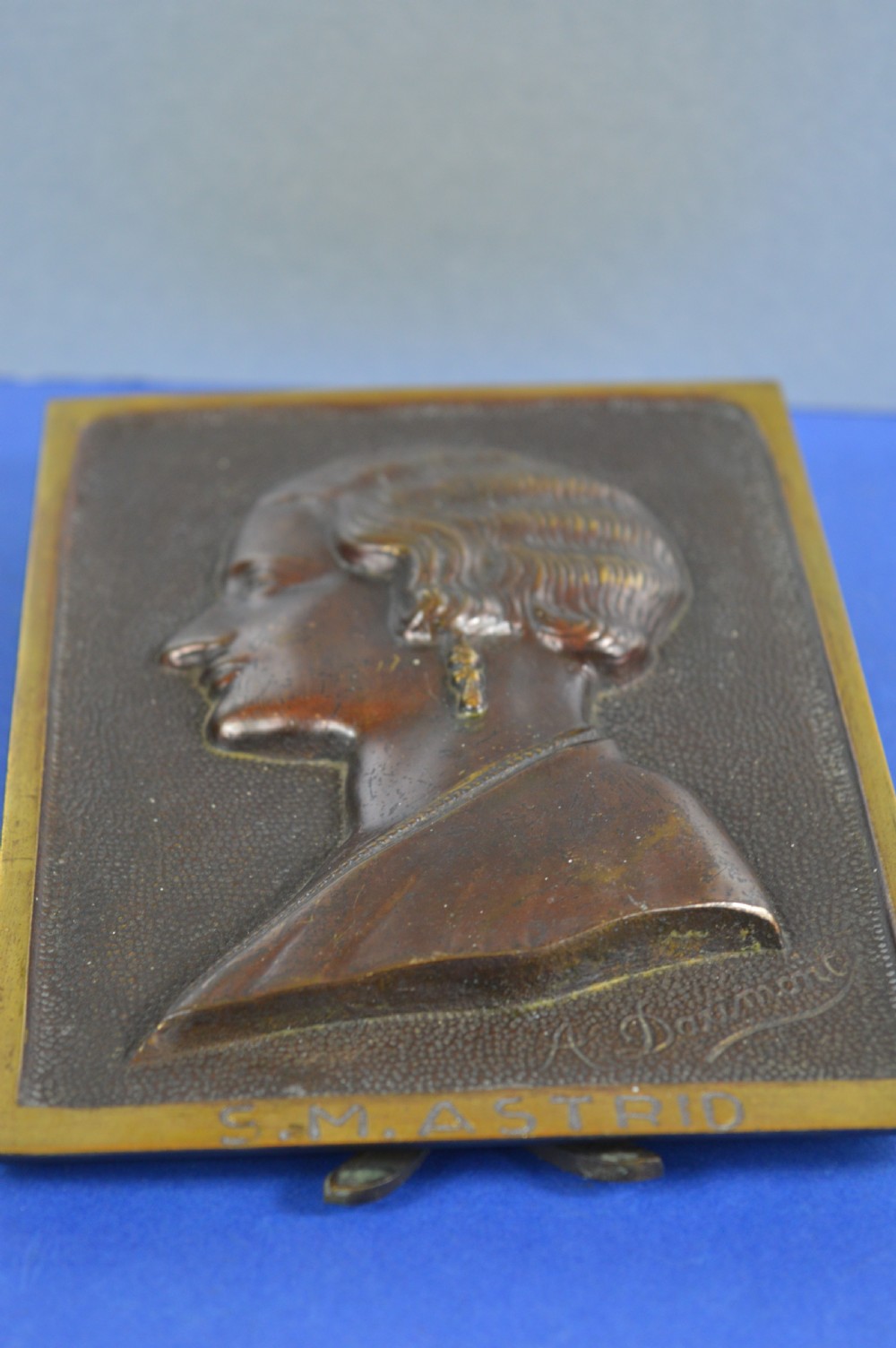 An Art Deco dark brown bronze relief plaque featuring a side profile portrait of Queen Astrid against a textured background with inscribed lettering. View VIII