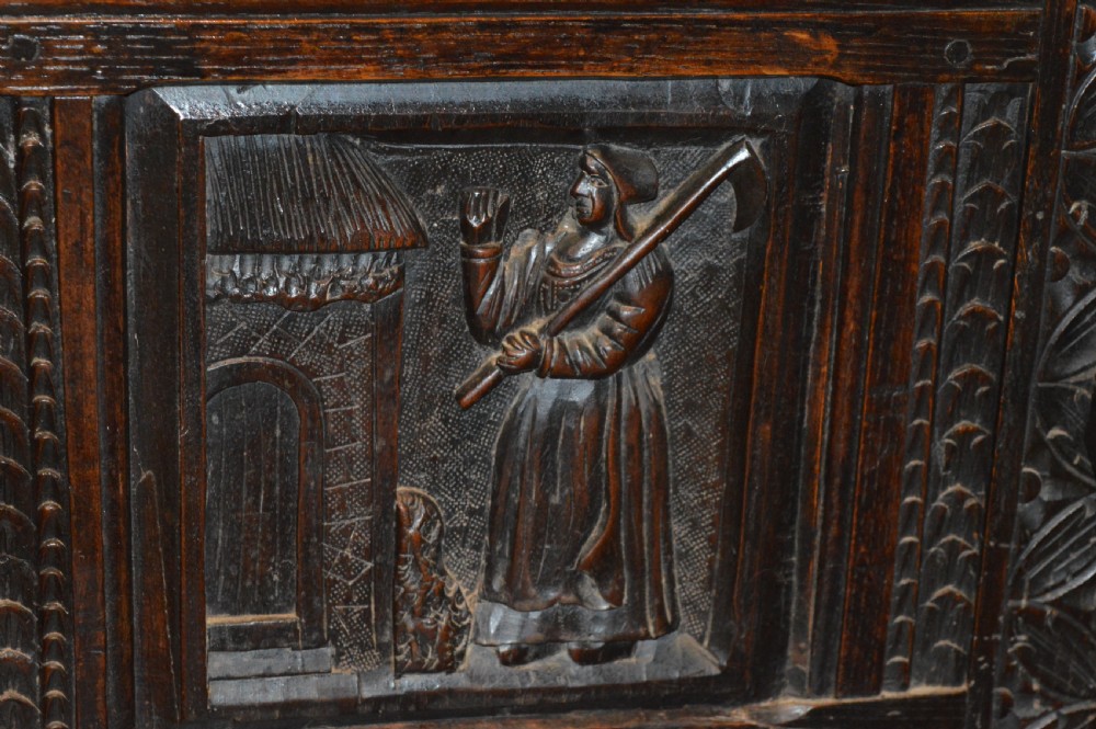 An 18th-century Flemish dark carved oak settle featuring figurative relief panels on the backrest and chest base with scrolled armrests. View VII