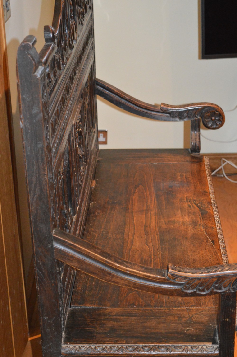 An 18th-century Flemish dark carved oak settle featuring figurative relief panels on the backrest and chest base with scrolled armrests. View XI