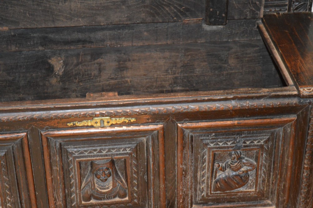 An 18th-century Flemish dark carved oak settle featuring figurative relief panels on the backrest and chest base with scrolled armrests. View XVII