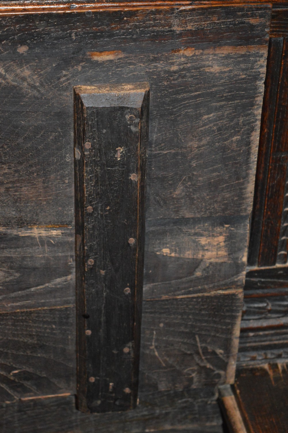 An 18th-century Flemish dark carved oak settle featuring figurative relief panels on the backrest and chest base with scrolled armrests. View XIX