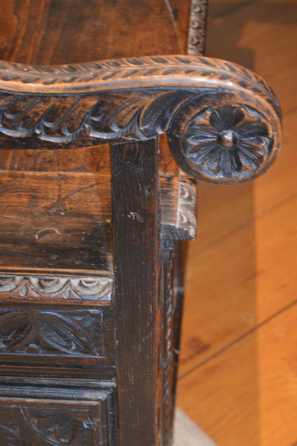 An 18th-century Flemish dark carved oak settle featuring figurative relief panels on the backrest and chest base with scrolled armrests. View XXI